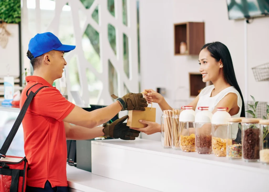 Courier picking up a box from a cashier in a restaurant for delivery
