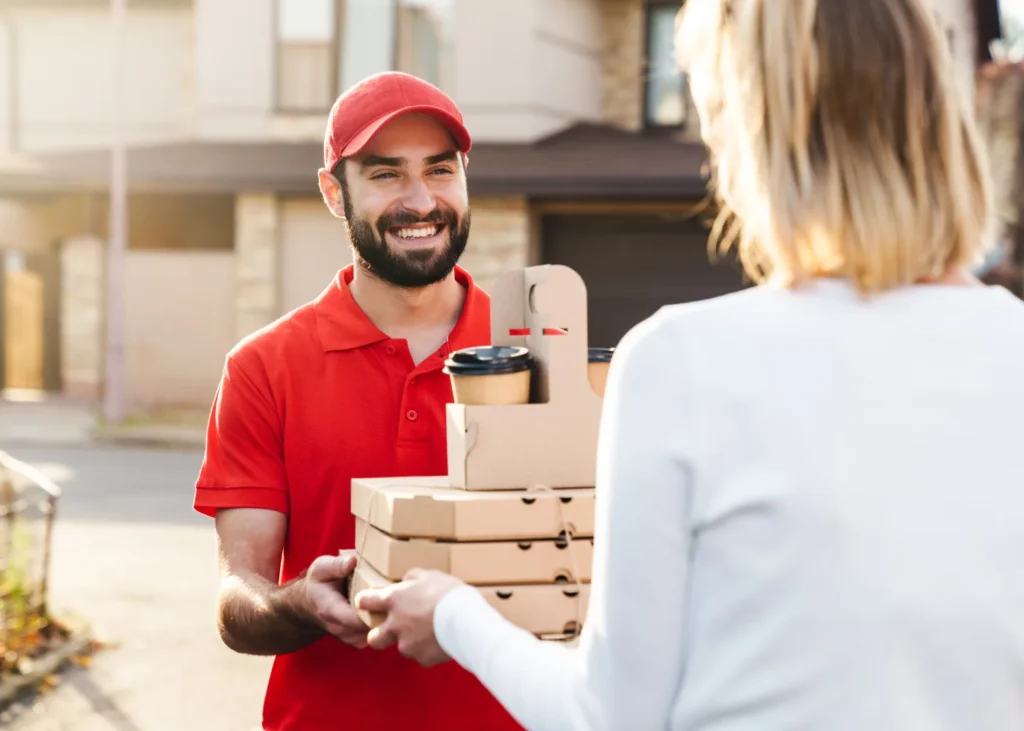Food courier delivering 3 boxes of pizza and hot drinks from a restaurant