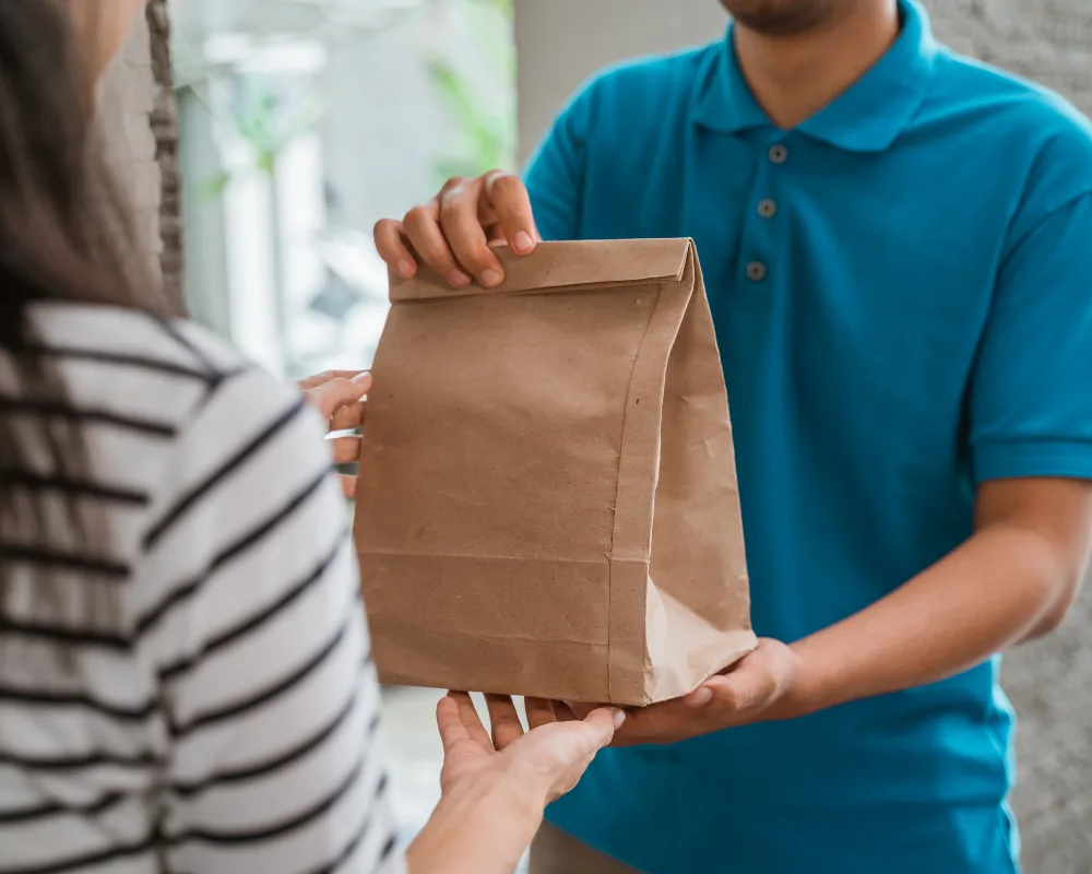 A courier delivering package packed in a paper bag